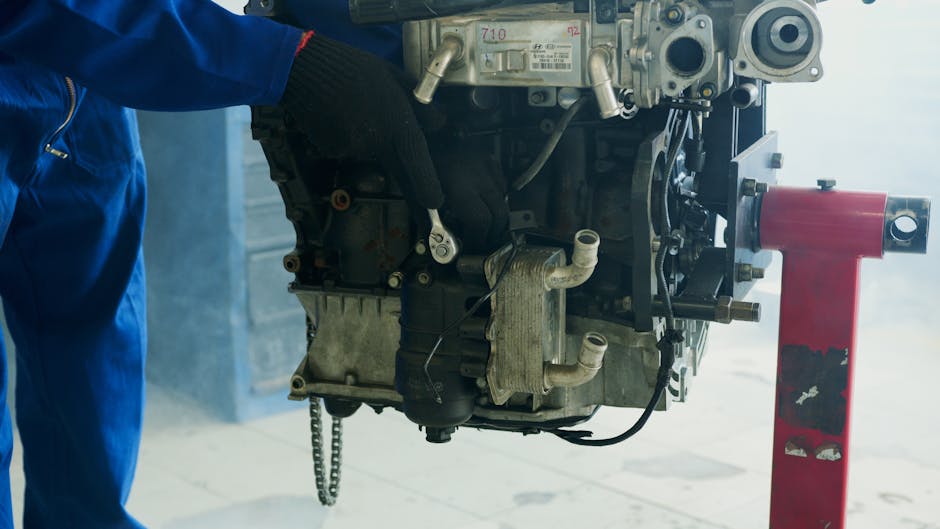 Mechanic wearing gloves uses a wrench to fix a car engine in a workshop.